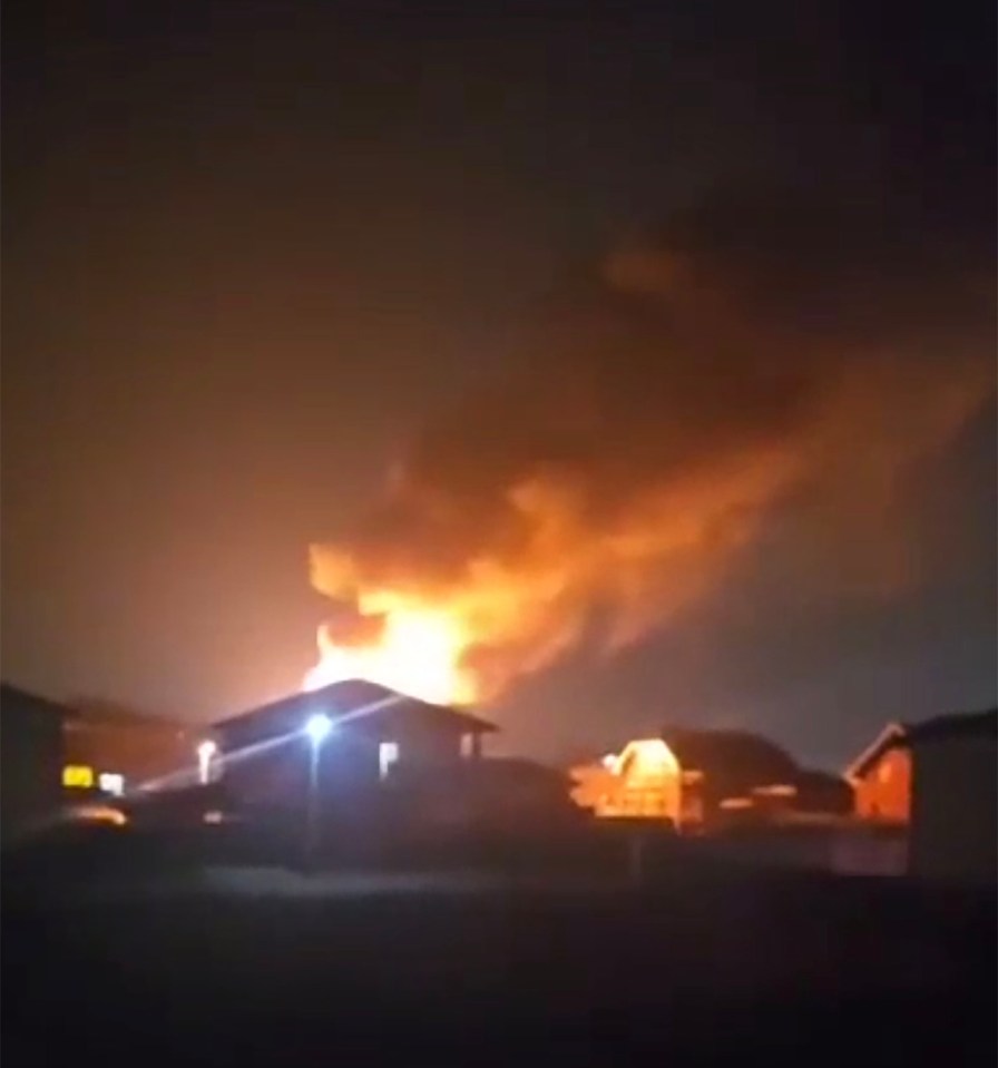 Large fire burning near buildings at night.