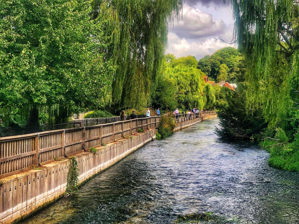 River Itchen Navigation in Hampshire, UK, with people walking along a wooden fence.