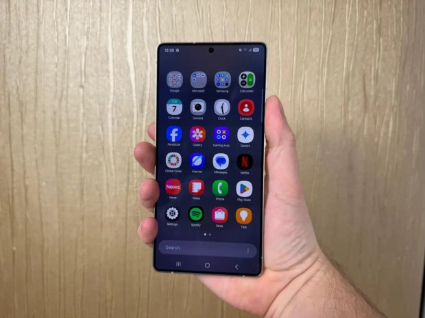 A hand holding a Samsung Galaxy S25 phone displaying various apps.