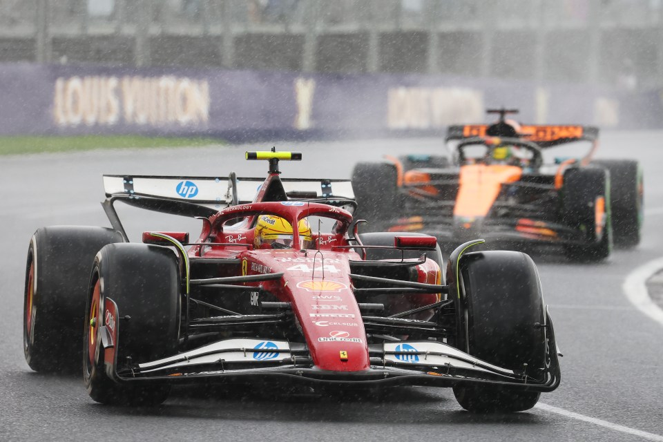 Lewis Hamilton's Ferrari leading another Formula 1 car in the rain.