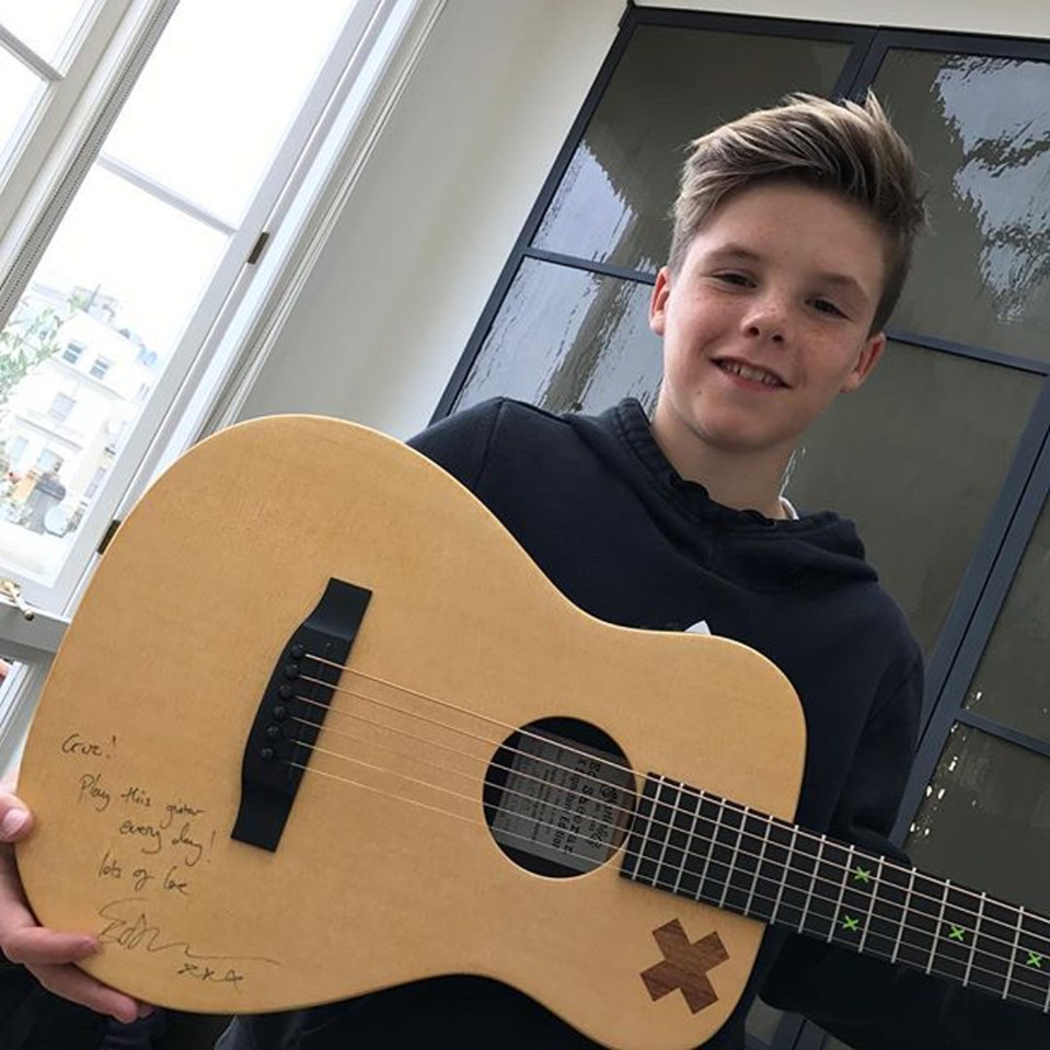 Boy holding a signed acoustic guitar.
