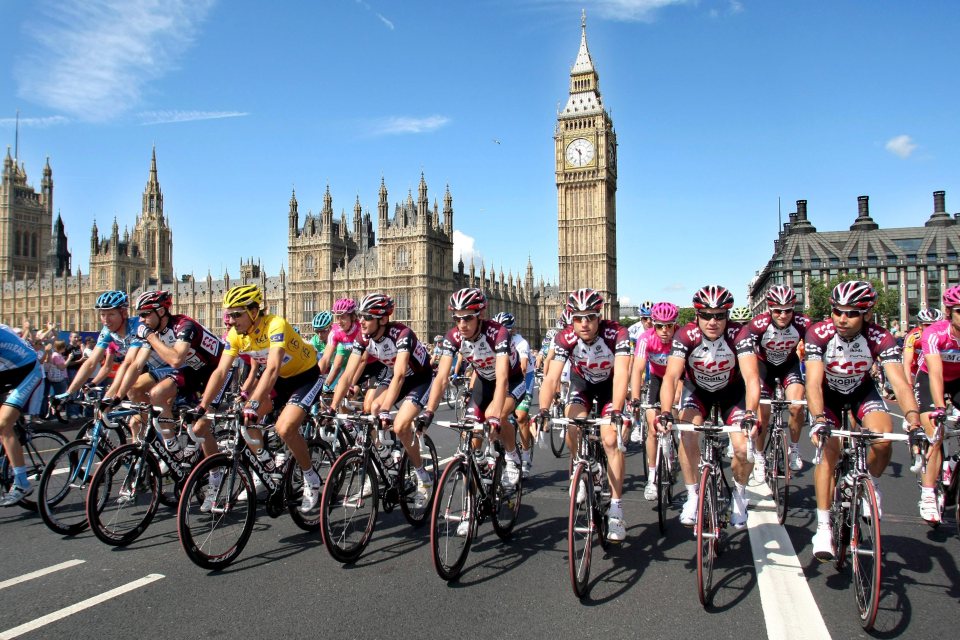 Team CSC cyclists riding past the Houses of Parliament and Big Ben in London.
