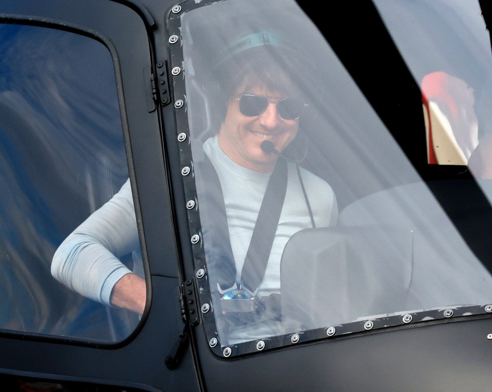 Tom Cruise smiling in a helicopter.