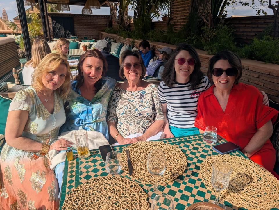 Five women seated at an outdoor table.