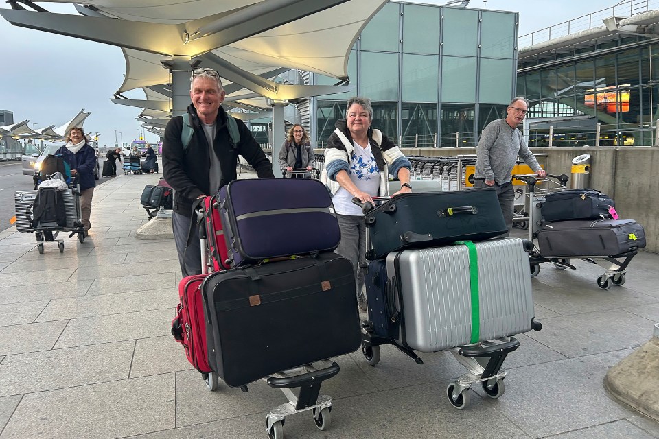 Travelers with luggage carts at an airport terminal.