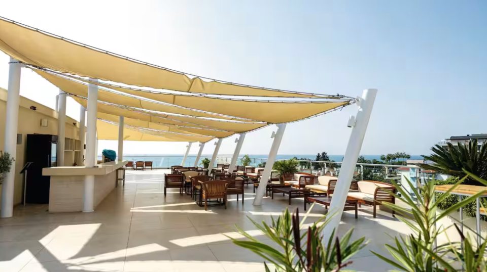 Outdoor lounge area with ocean view and shade sails.