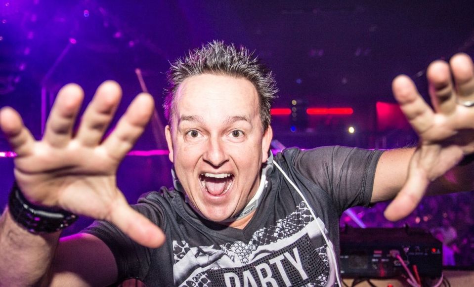 A DJ with his hands outstretched at a party.
