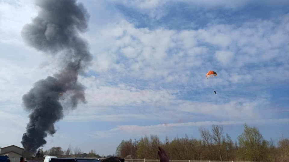 Pilot parachuting near a large smoke plume from a plane crash.