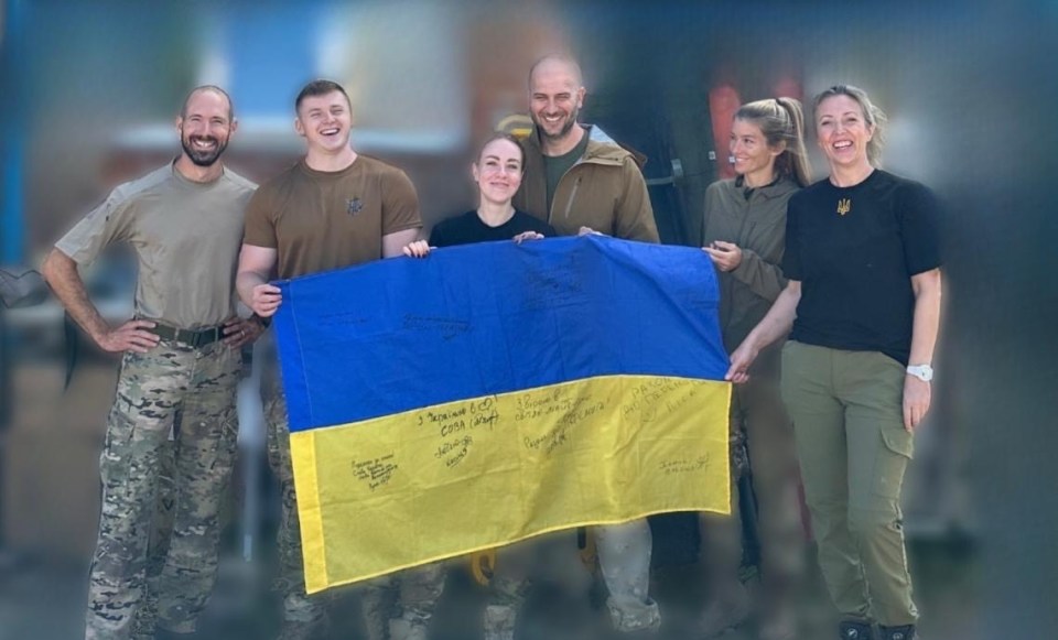 Ukrainian frontline medics holding a signed Ukrainian flag.