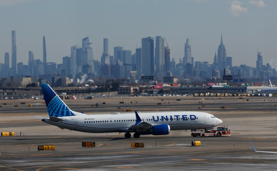 United Airlines airplane being towed at Newark Liberty International Airport with the New York City skyline in the background.