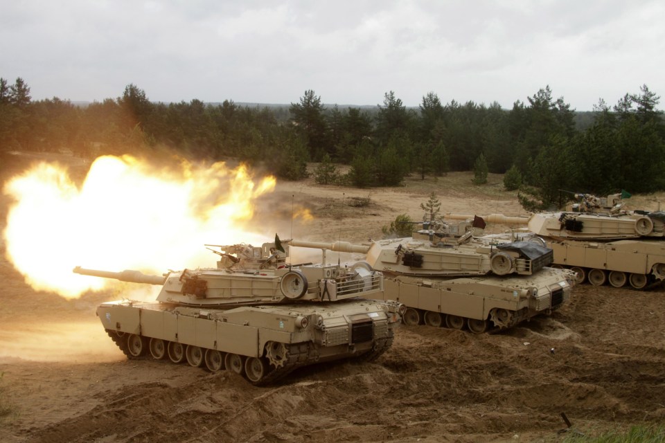 US Army M1 Abrams tanks firing during military exercises.