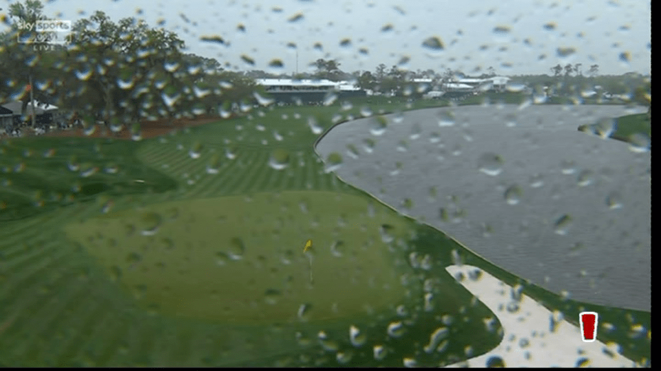 Rainy view of a golf course seen through a rain-covered window.