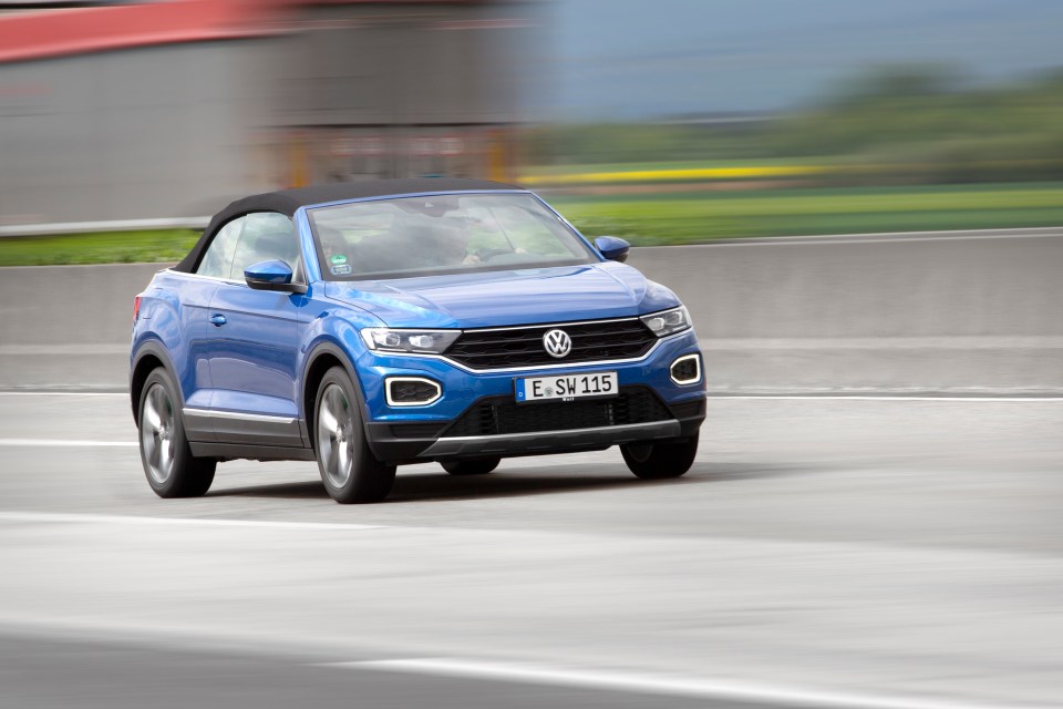 Blue Volkswagen T-Roc Cabriolet driving on a highway.