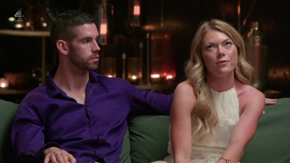 A man and woman sitting on a couch, appearing emotional.