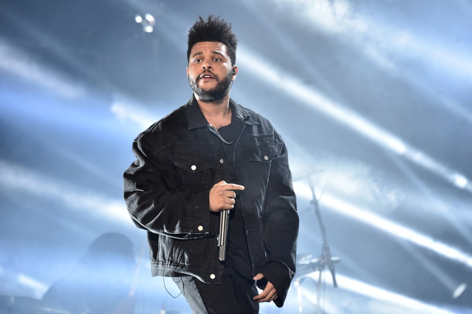 The Weeknd performing onstage at a concert.