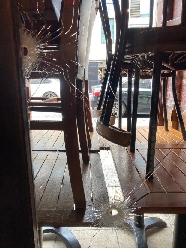 Bullet holes in the window of a restaurant.