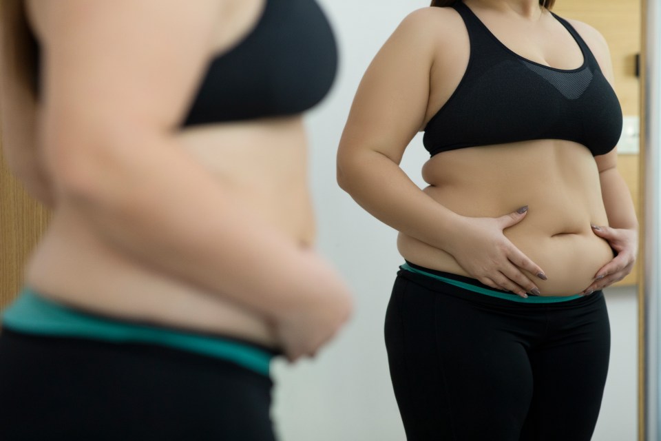 Woman looking at her abdomen in a mirror.