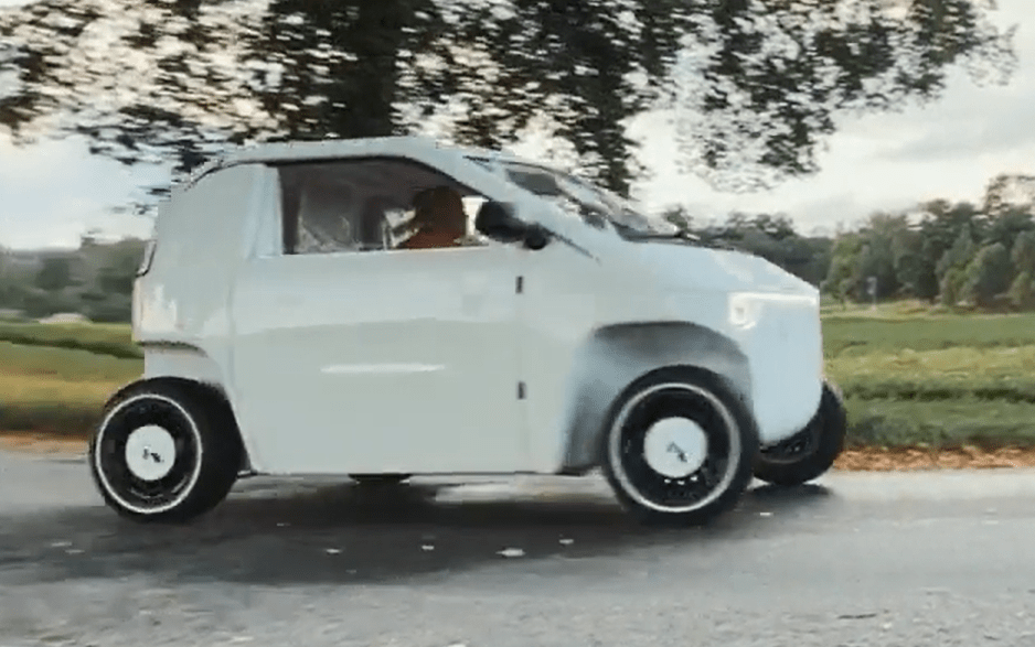 White Luvly flat-pack car driving on a road.
