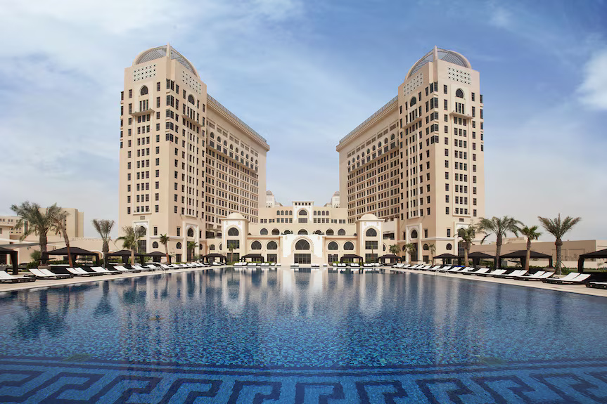 The St. Regis Doha hotel with a large pool in front.