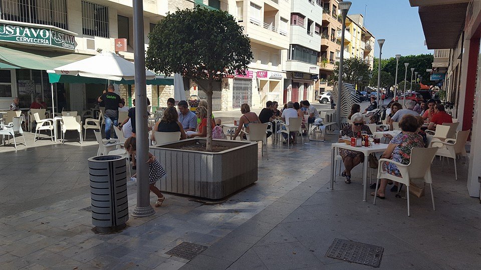 People sitting at tables outside a cafe in Almoradí, Spain.