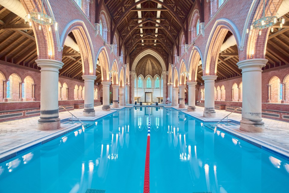 Indoor swimming pool in a brick building with arched ceilings and columns.