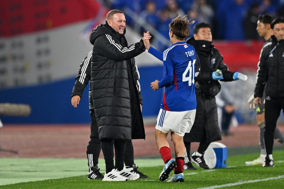 Soccer player and coach high-fiving after a goal.