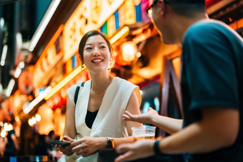 Young Asian couple enjoying drinks in a Tokyo alleyway.