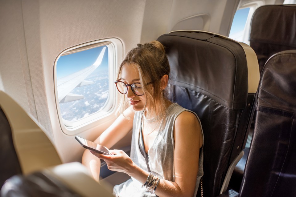 Woman using a phone on an airplane.