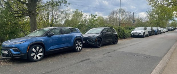 Row of abandoned electric 4x4s parked on a road.