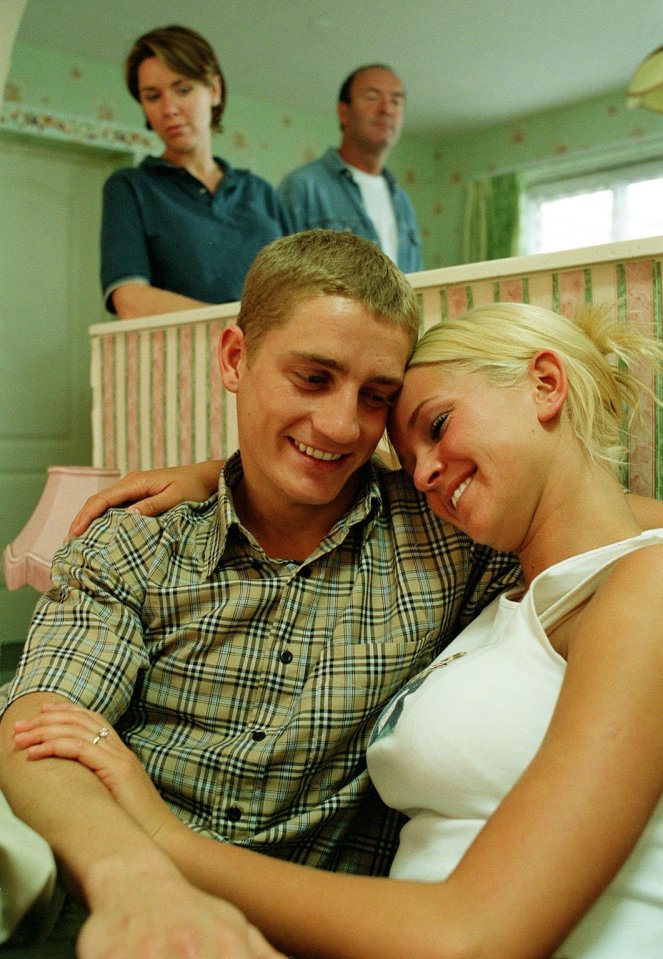 Tim and Emily embrace in a room.  Two other people are visible in the background.