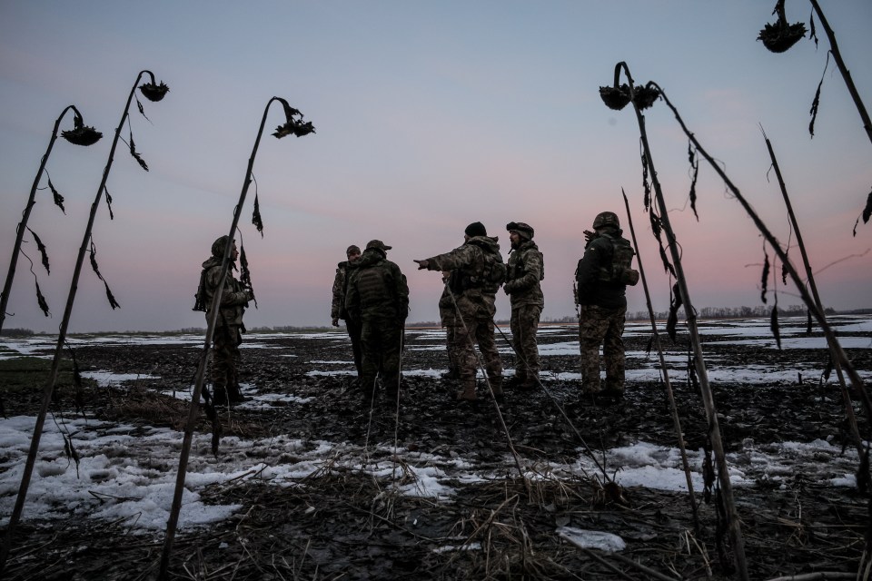 Ukrainian soldiers in a field after an air raid.