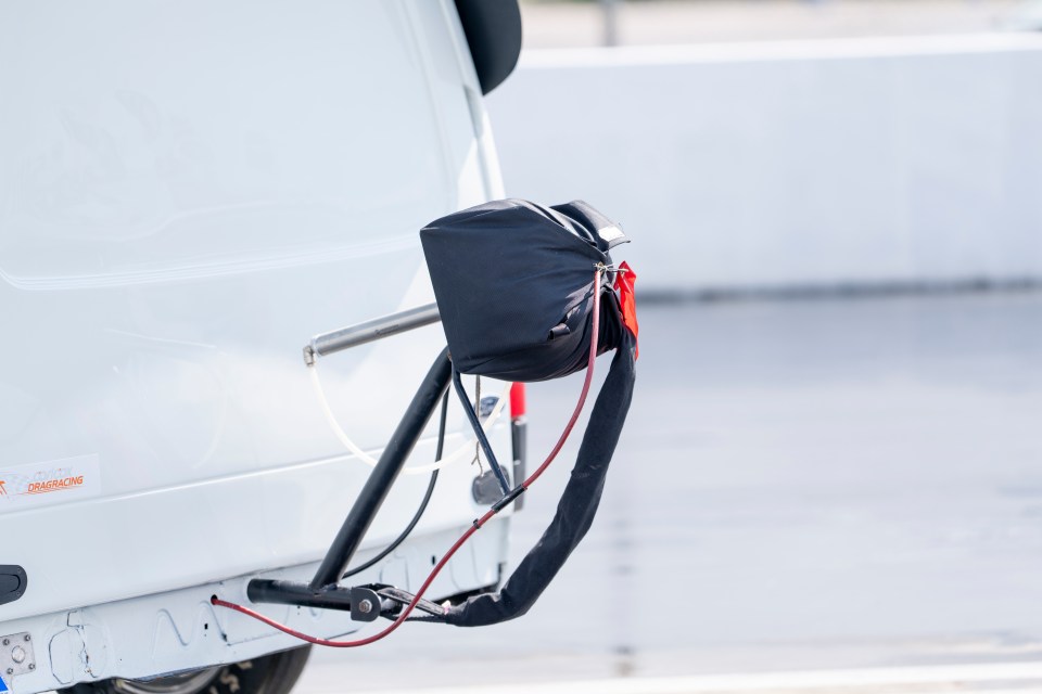 A parachute attached to the back of a drag racing van.