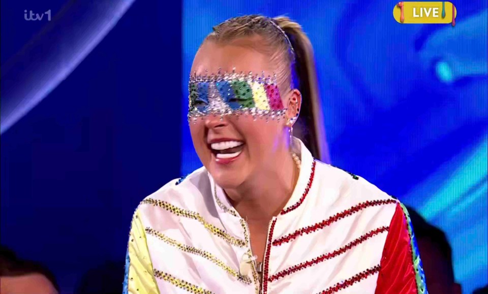 JoJo Siwa on Celebrity Big Brother, wearing a colorful jeweled mask.