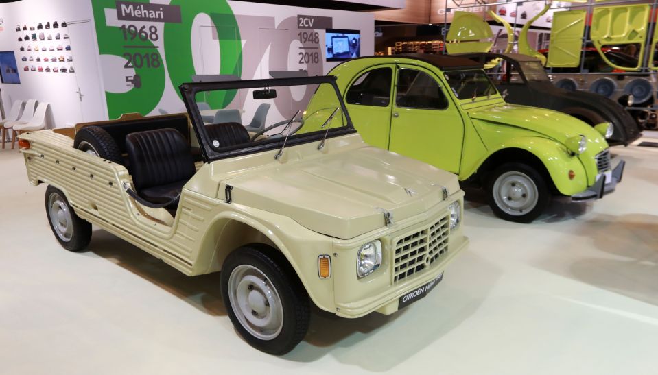 A beige Citroën Méhari and a lime green Citroën 2CV on display at a car show.