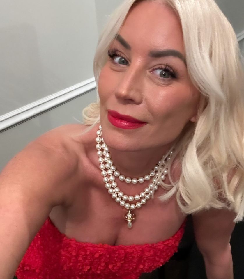 Denise Van Outen at a gala, wearing a red dress and pearl necklace.