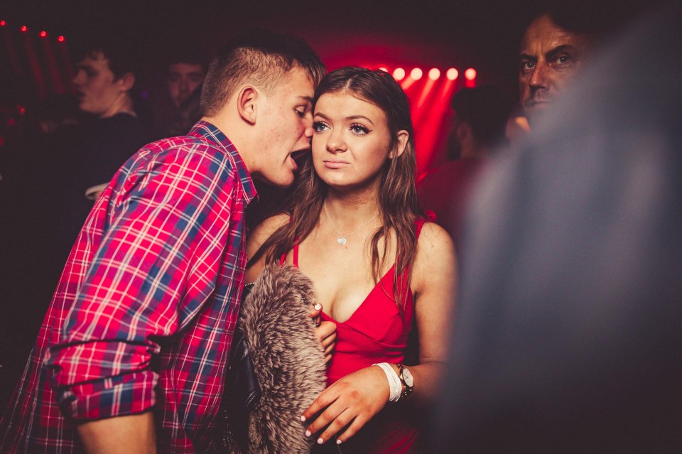 Woman looking unimpressed while a man whispers in her ear.