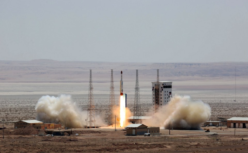 Satellite rocket launching from a desert launchpad.