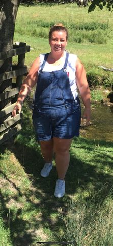 Woman in denim overalls walking outdoors.