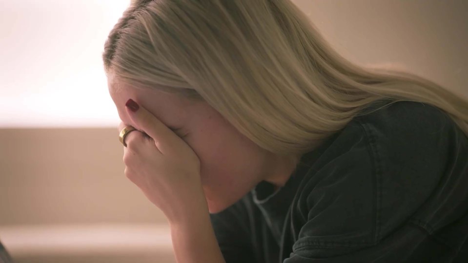 Woman with blonde hair covering her face with her hand.