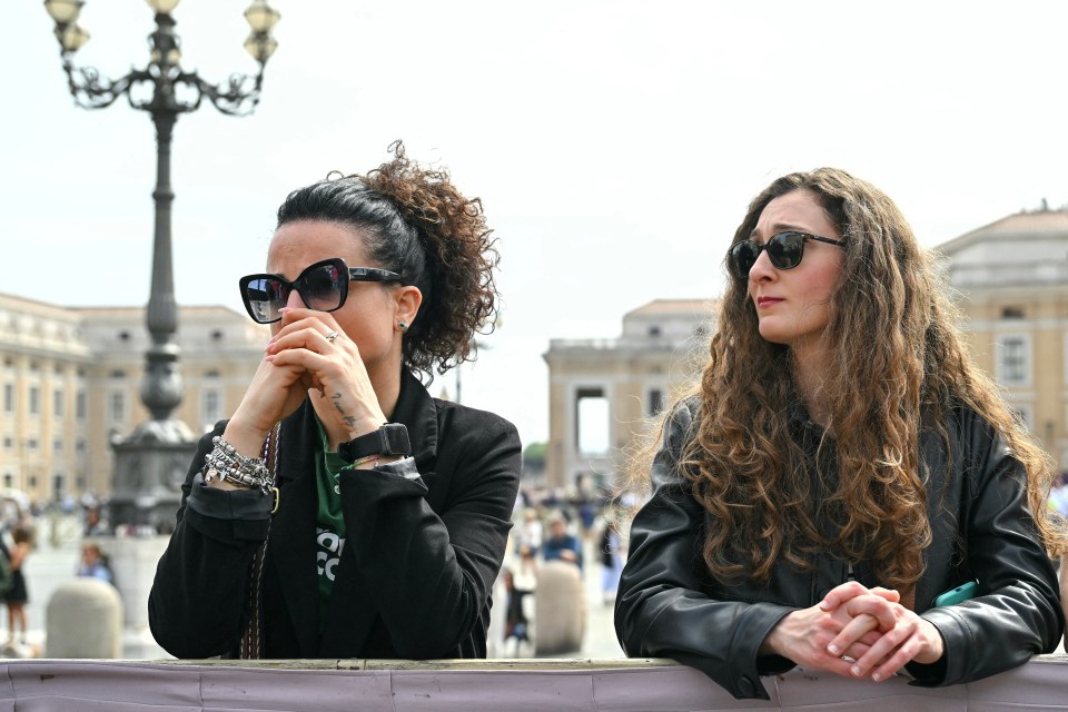 Two women mourn in St. Peter's Square following the death of Pope Francis.