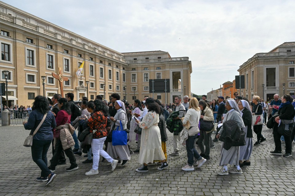 Mourners carrying a wooden cross walk towards St. Peter's Square.