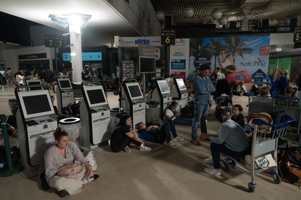 Passengers sitting on the floor of an airport during a widespread power outage.