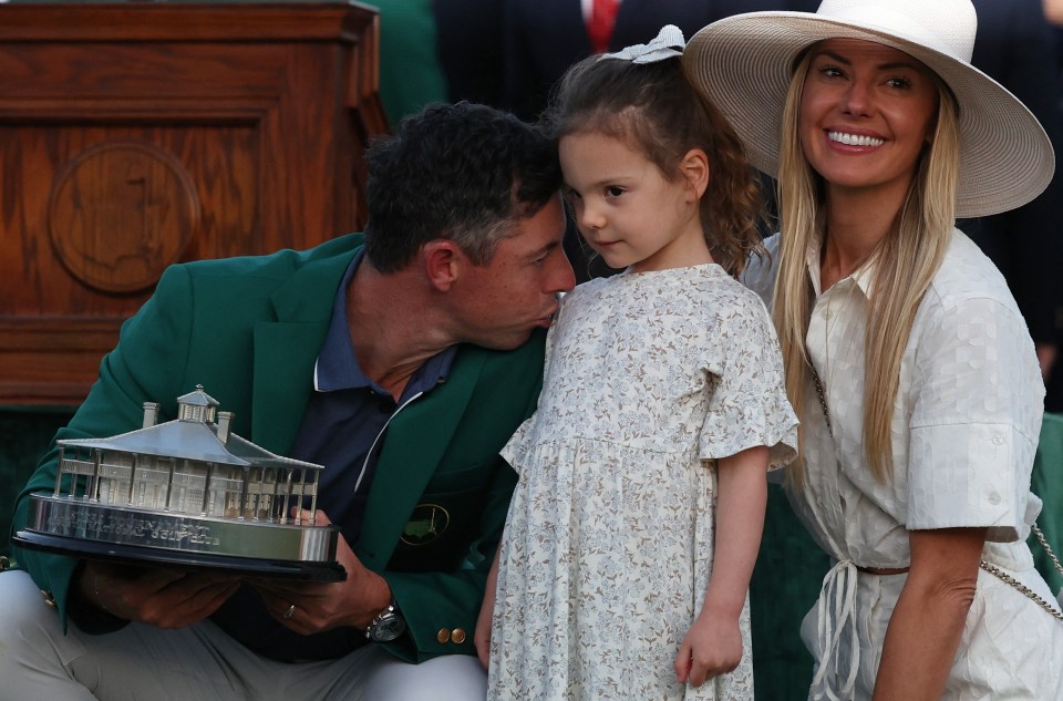 Rory McIlroy kisses his daughter while holding the Masters Tournament trophy with his wife.