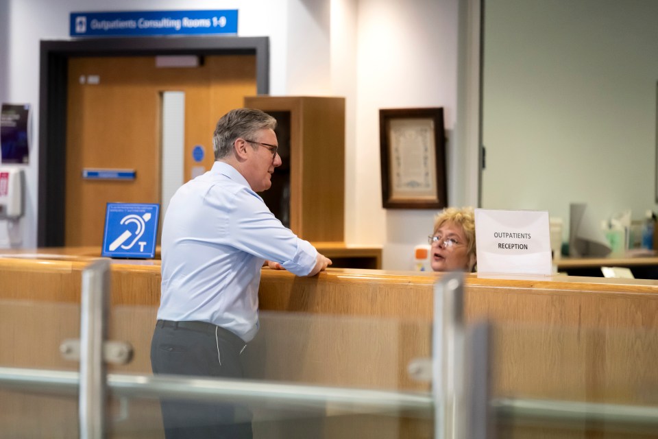 Prime Minister Keir Starmer speaking with a receptionist at a health center.