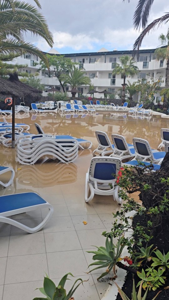 Flooded pool area with submerged lounge chairs.