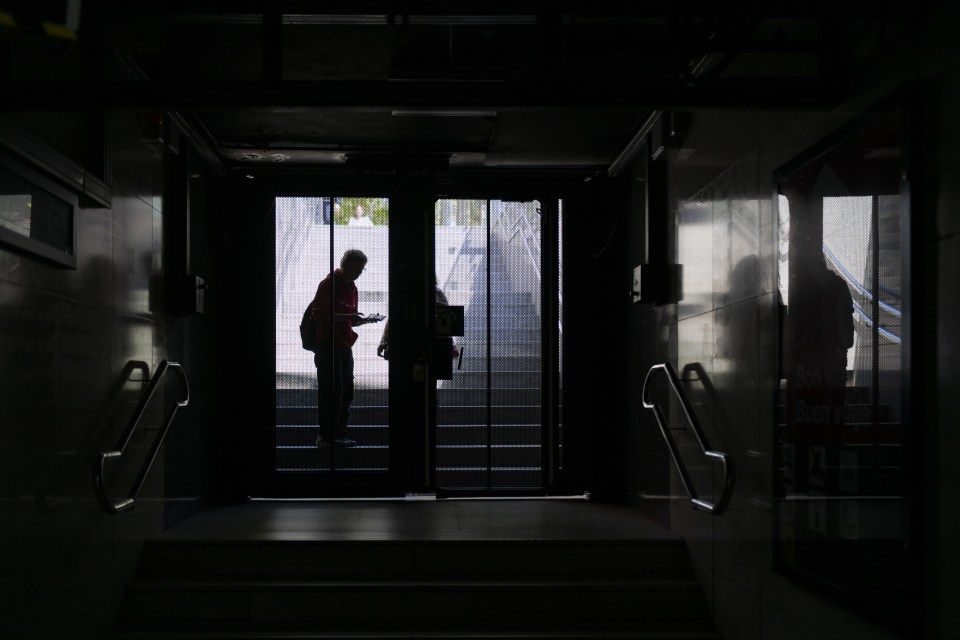 Silhouetted figures at a closed metro station gate during a power outage.