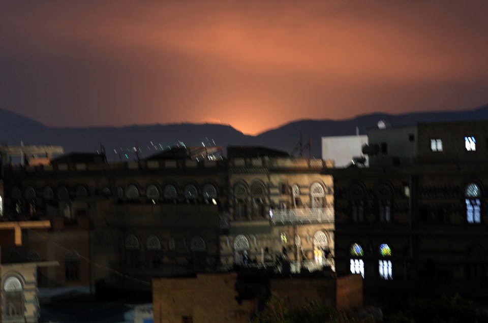 Nighttime view of Sana'a, Yemen, with an orange glow in the sky.