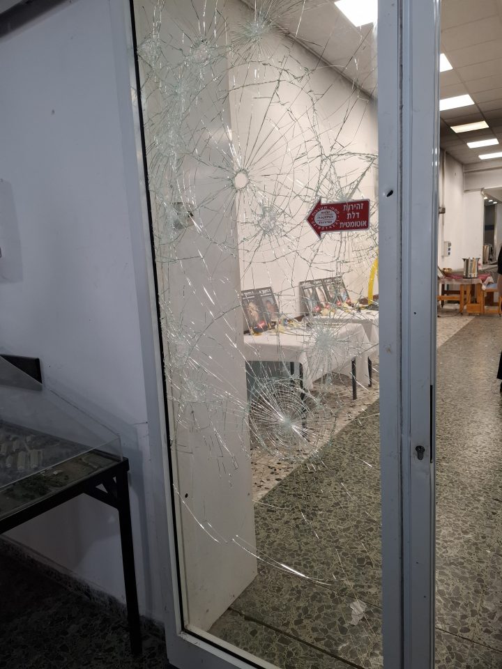 Shattered glass door with bullet holes.