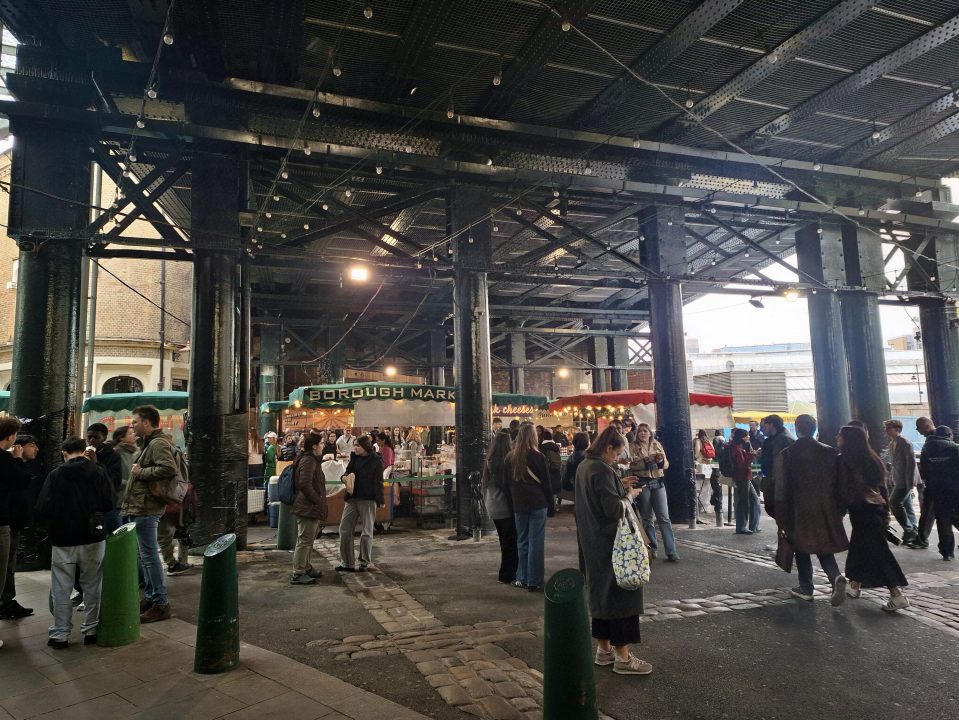 People shopping at Borough Market under a metal structure.