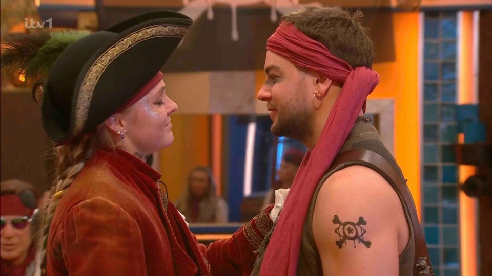 Two people in pirate costumes embrace.